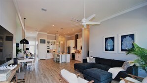 A modern living room with a dark blue sofa, wooden chairs, and a dining area with a white table and chairs.