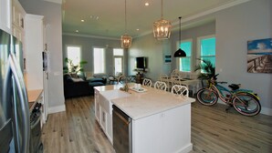 A spacious kitchen with a central island, a dining area with a table and chairs, and a bicycle in the background.