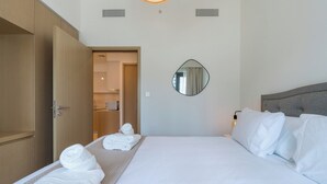 Hotellihuone, jossa on suuri sänky, yöpöytä, peili ja vaatekaappi.