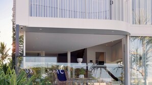 Une maison moderne à deux étages, dotée d’un balcon, d’un espace extérieur aménagé et d’un jardin bien entretenu.