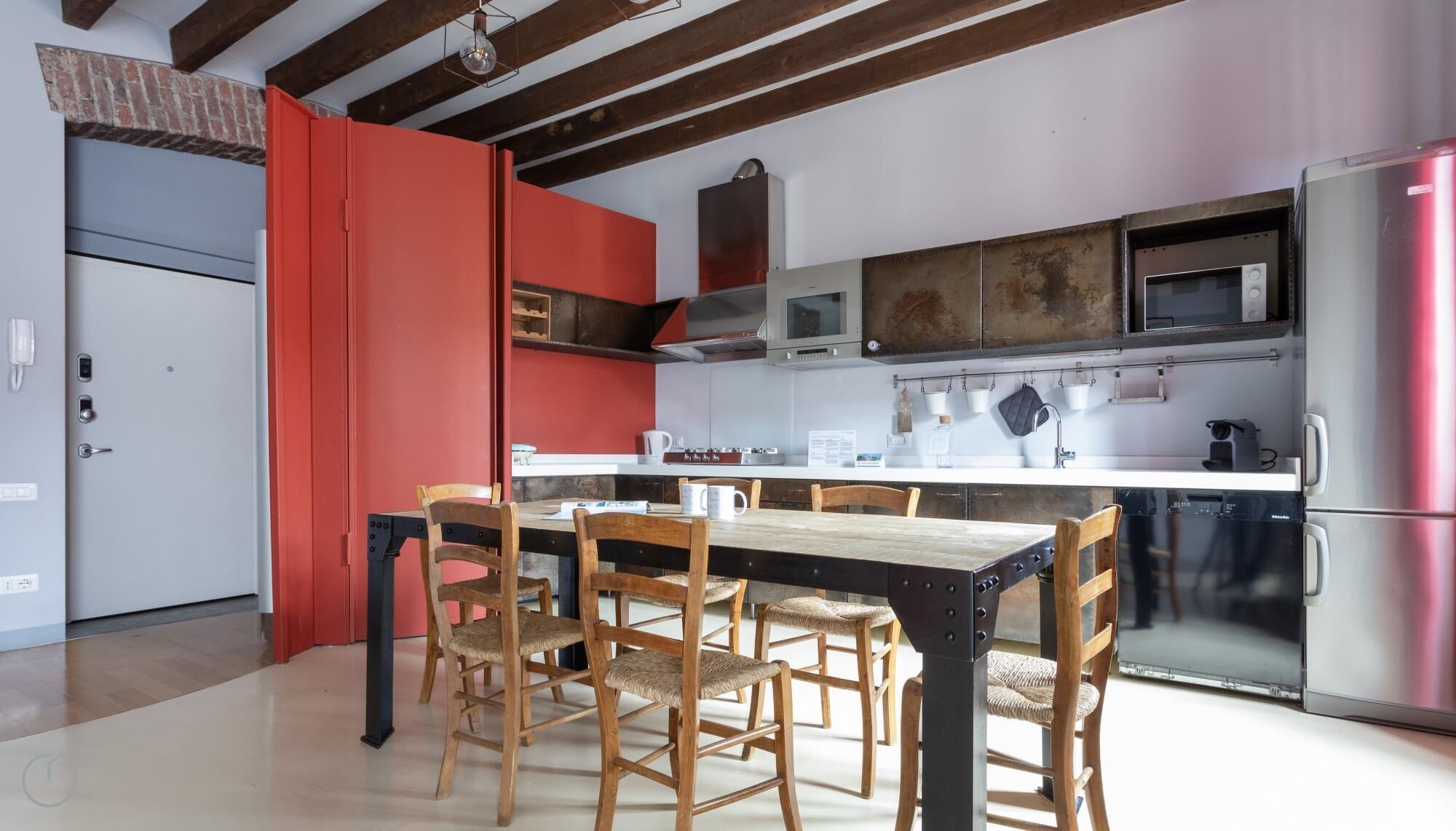 A modern kitchen with a wooden dining table, four chairs, and stainless steel appliances.