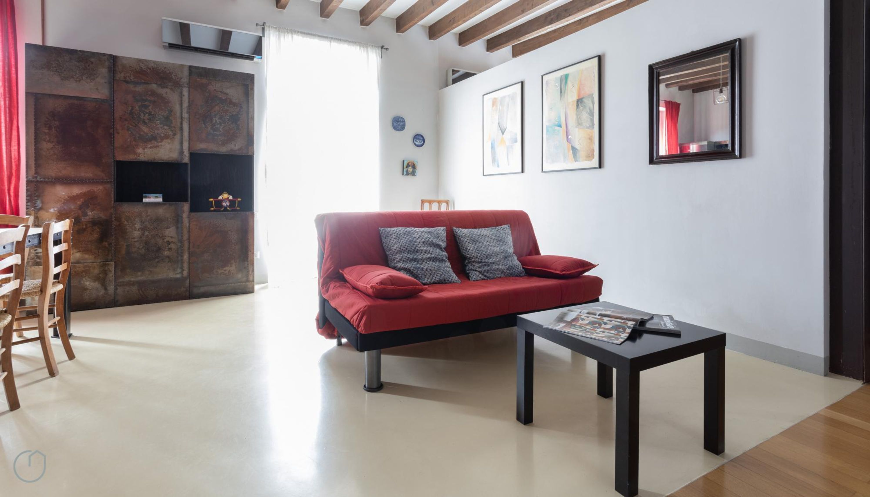 Un salon moderne avec un canapé rouge, une table basse et un coin repas avec des chaises en bois.