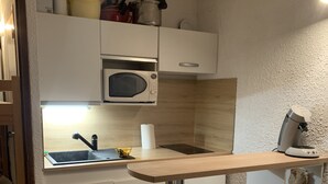 Eine kleine Küche mit Spüle, zwei Mikrowellen und einer Arbeitsplatte.