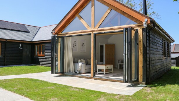 A modern house with a glass front, wooden exterior, and a well-maintained lawn. - Robins Nest (Fareham)