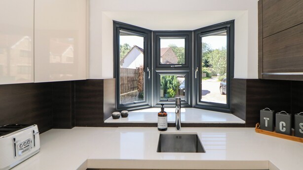 A modern kitchen with a corner window, a built-in stove, and a sink with a soap dispenser. - Millhouses Hideaway (Sheffield)