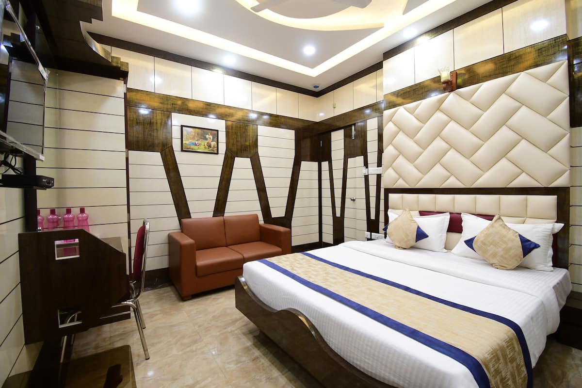 Ein Hotelzimmer mit einem großen Bett, einem braunen Ledersofa, einem Holzschminktisch und einem Spiegel.