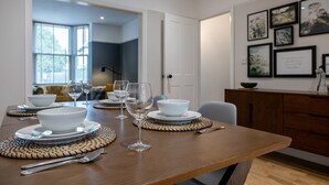Comedor con una mesa de madera preparada para cuatro personas, con cuencos, platos y copas de vino.