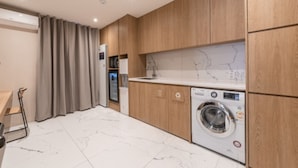 Une cuisine moderne avec des meubles en bois, un lave-linge encastré et un pare-feu en marbre.