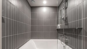 Une salle de bain moderne avec une baignoire sur pieds, un espace douche et un mur recouvert de carreaux.