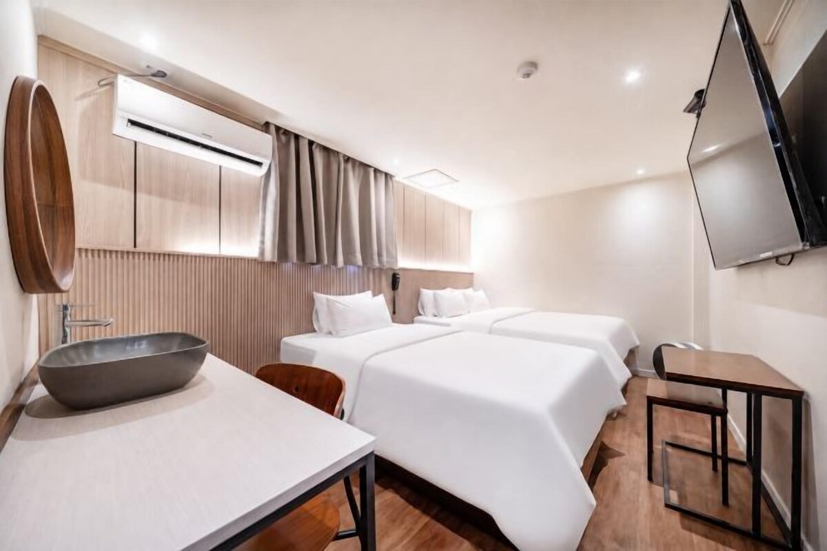 Una habitación de hotel con una cama, un escritorio, una silla, un televisor y un equipo de aire acondicionado.