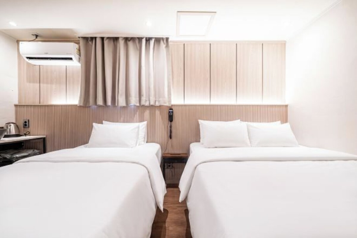 Una habitación de hotel con dos camas, un escritorio y una ventana con cortinas.
