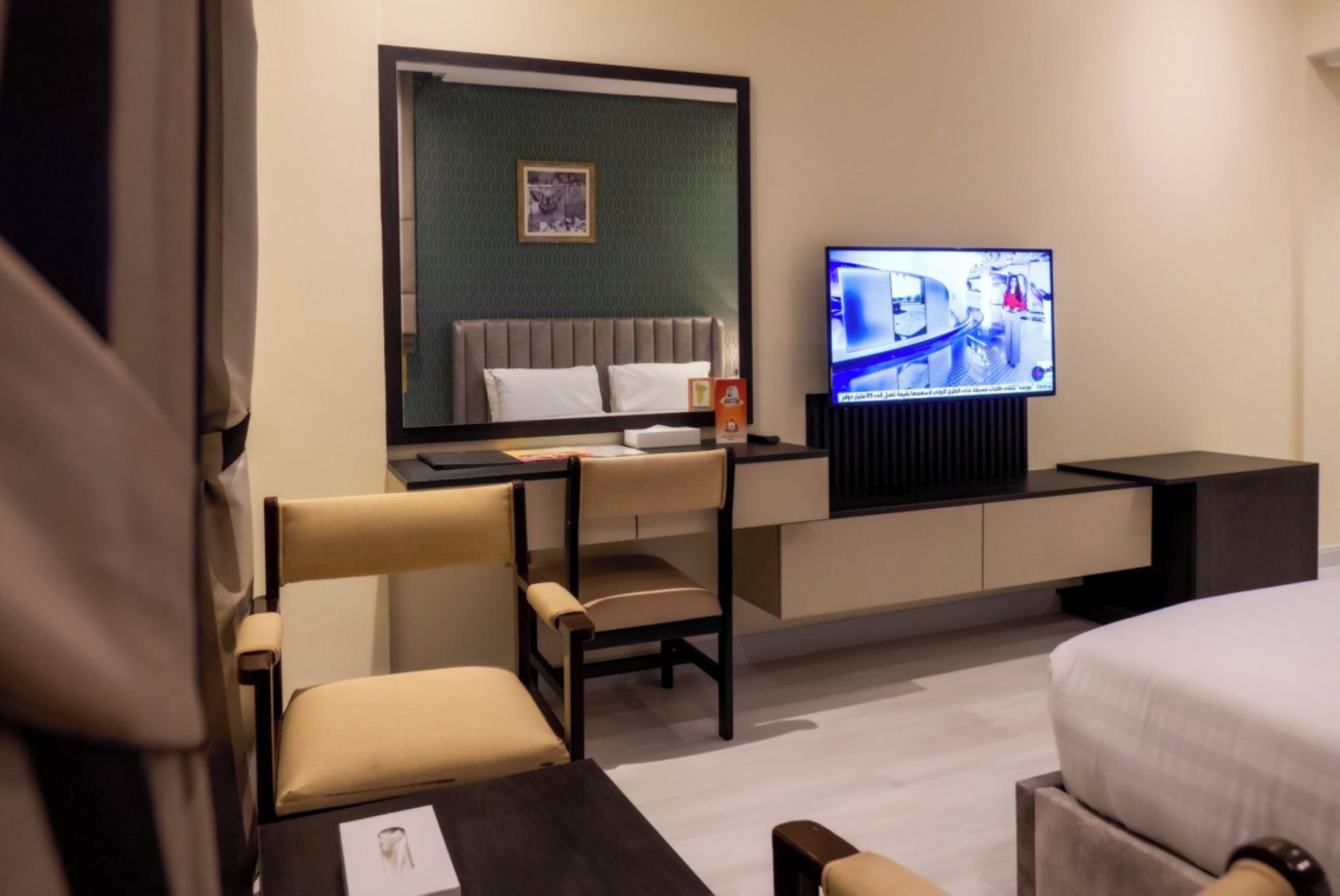 A hotel room with a bed, a desk with a chair, a television, and a small table.