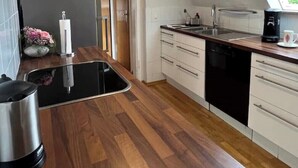 A modern kitchen with a wooden countertop, a built-in stove, and a window providing natural light.