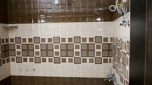 A bathroom with a checkered floor, a white toilet, and patterned tiles on the walls. - Hotel Abodes House (Noida)