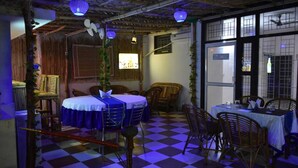 A dining area with checkered flooring, wooden furniture, and a rustic ceiling. - Hotel Abodes House (Noida)