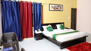 A bedroom with a bed, nightstand, and a desk with a chair. - Hotel Abodes House (Noida)