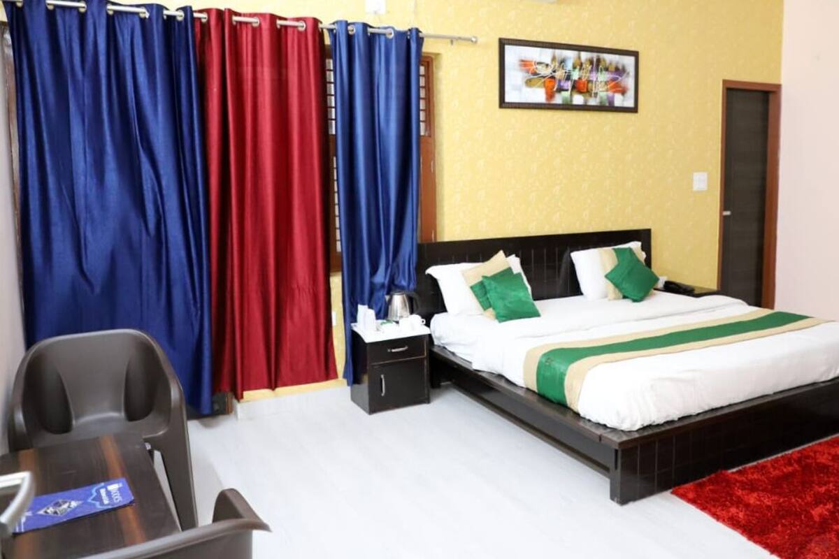 A bedroom with a bed, nightstand, and a desk with a chair.