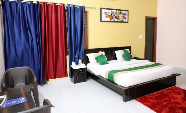 A bedroom with a bed, nightstand, and a desk with a chair.