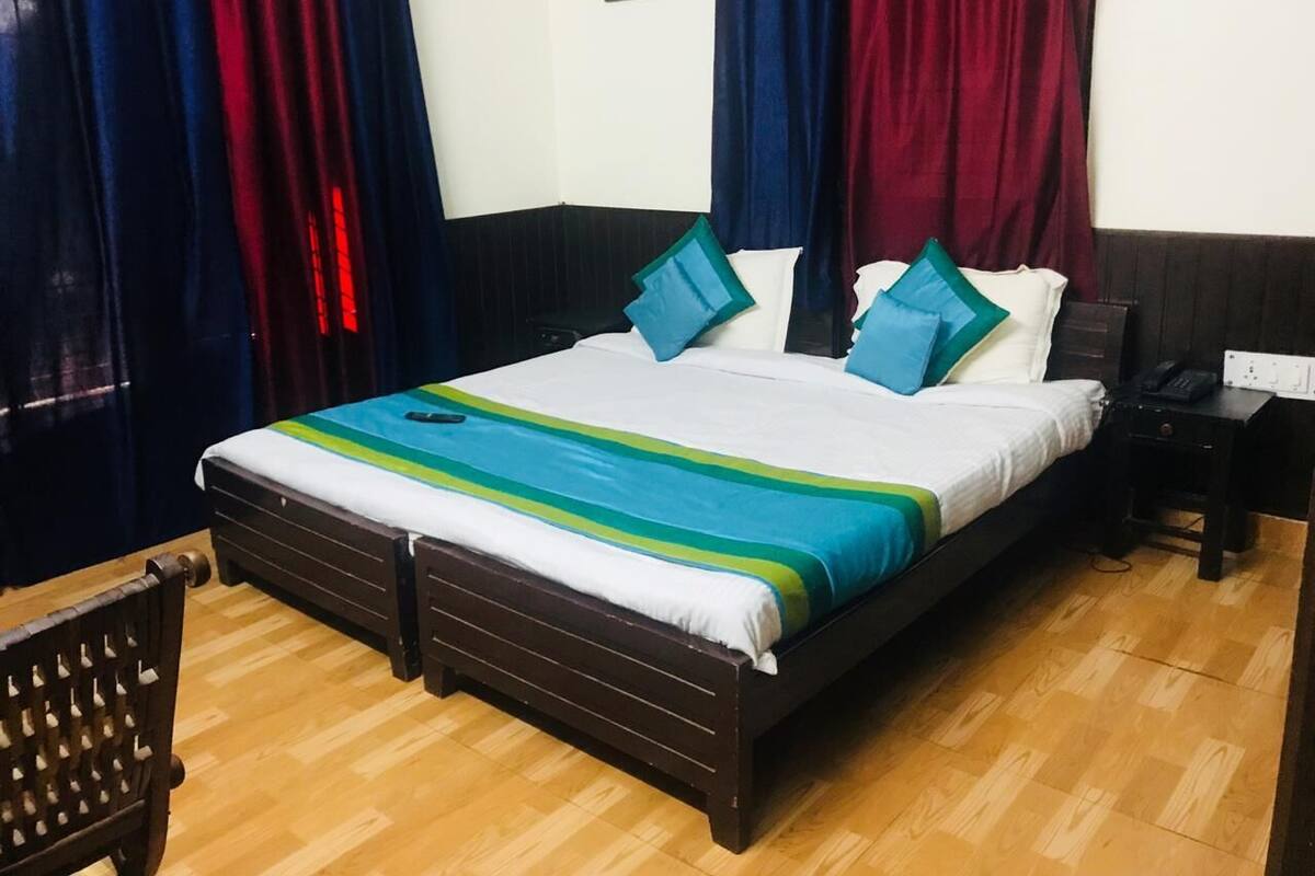 A neatly arranged bedroom with a large bed, a bedside table, a chair, and curtains.