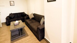 Uma sala de estar com um sofá marrom escuro, uma mesinha de centro e um quadro na parede.