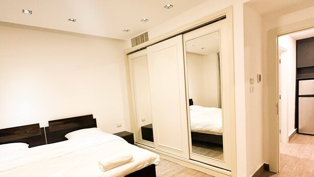 Quarto moderno com cama, guarda-roupa e espelho.