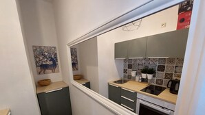 Une cuisine étroite avec un plan de travail en bois, un évier et une cuisinière. Le mur derrière l’évier est décoré de carreaux et un tableau est accroché au mur.