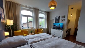 Une chambre d’hôtel avec un grand lit, une télévision, un bureau et une fenêtre avec des rideaux.