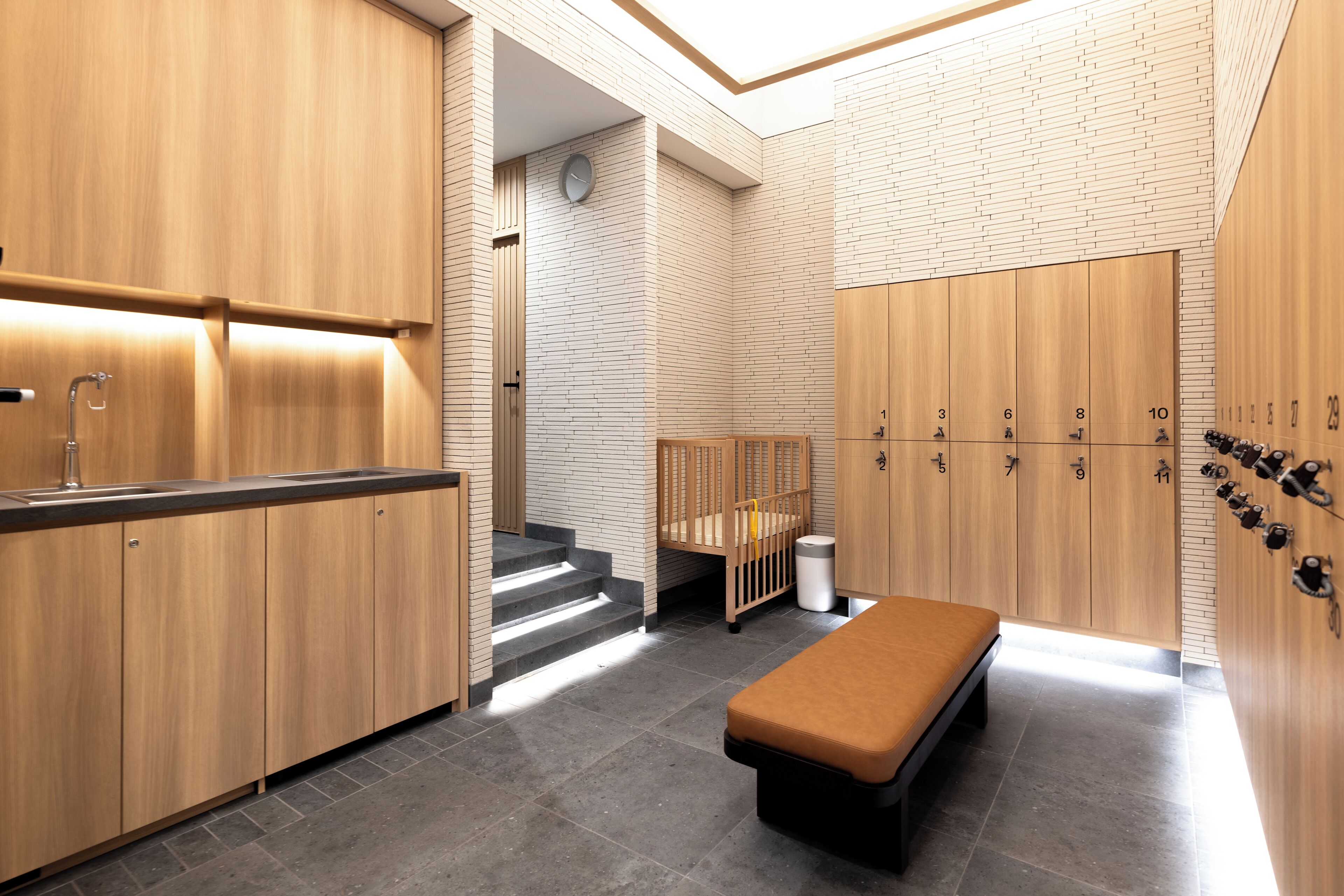 A modern bathroom with wooden cabinets, a bench, and a shower area.
