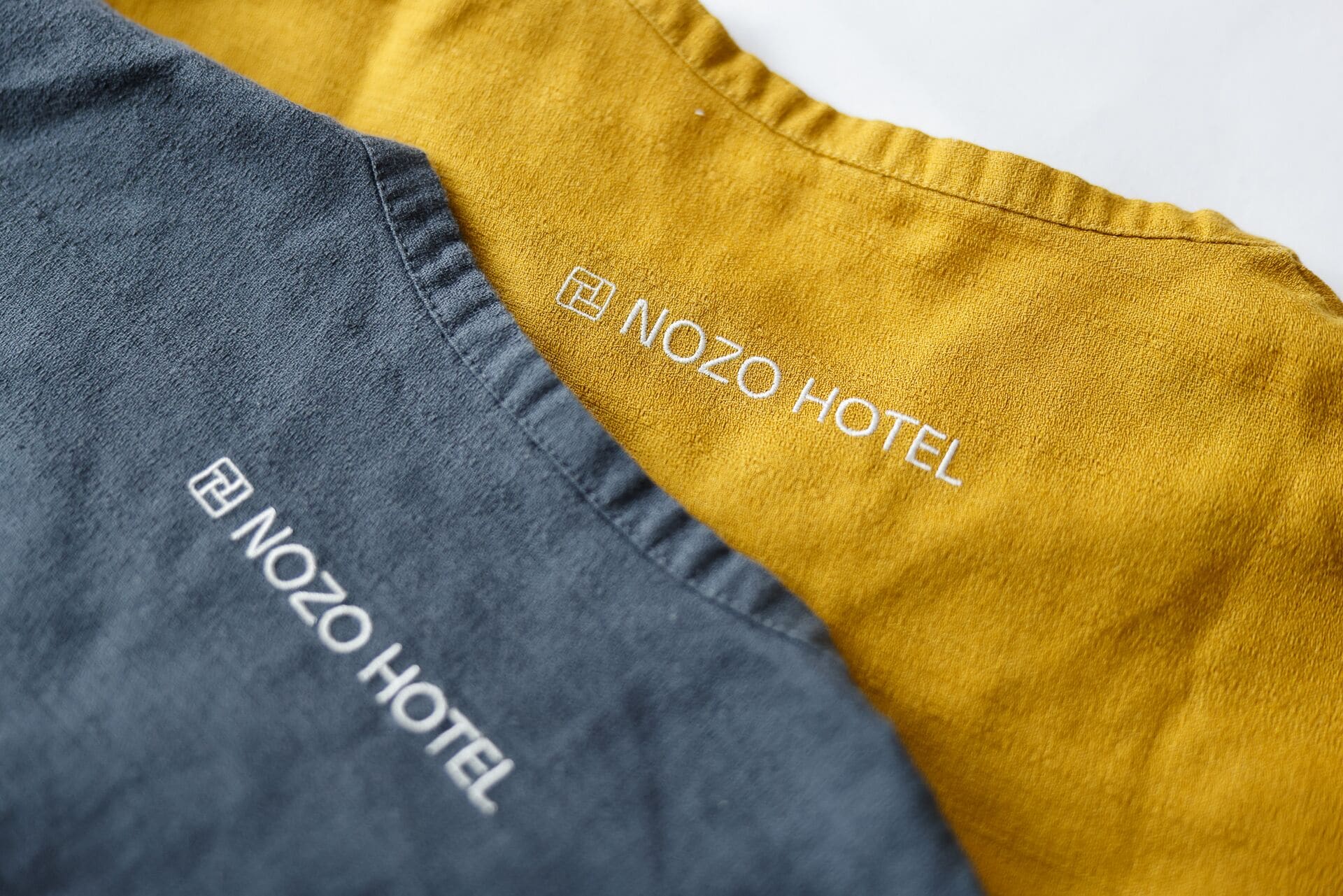 Primer plano de dos trozos de tela con el texto 'NOZO HOTEL' bordado.
