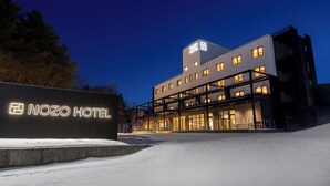 Een modern hotel met een opvallend bord, meerdere verdiepingen en een met sneeuw bedekte grond.