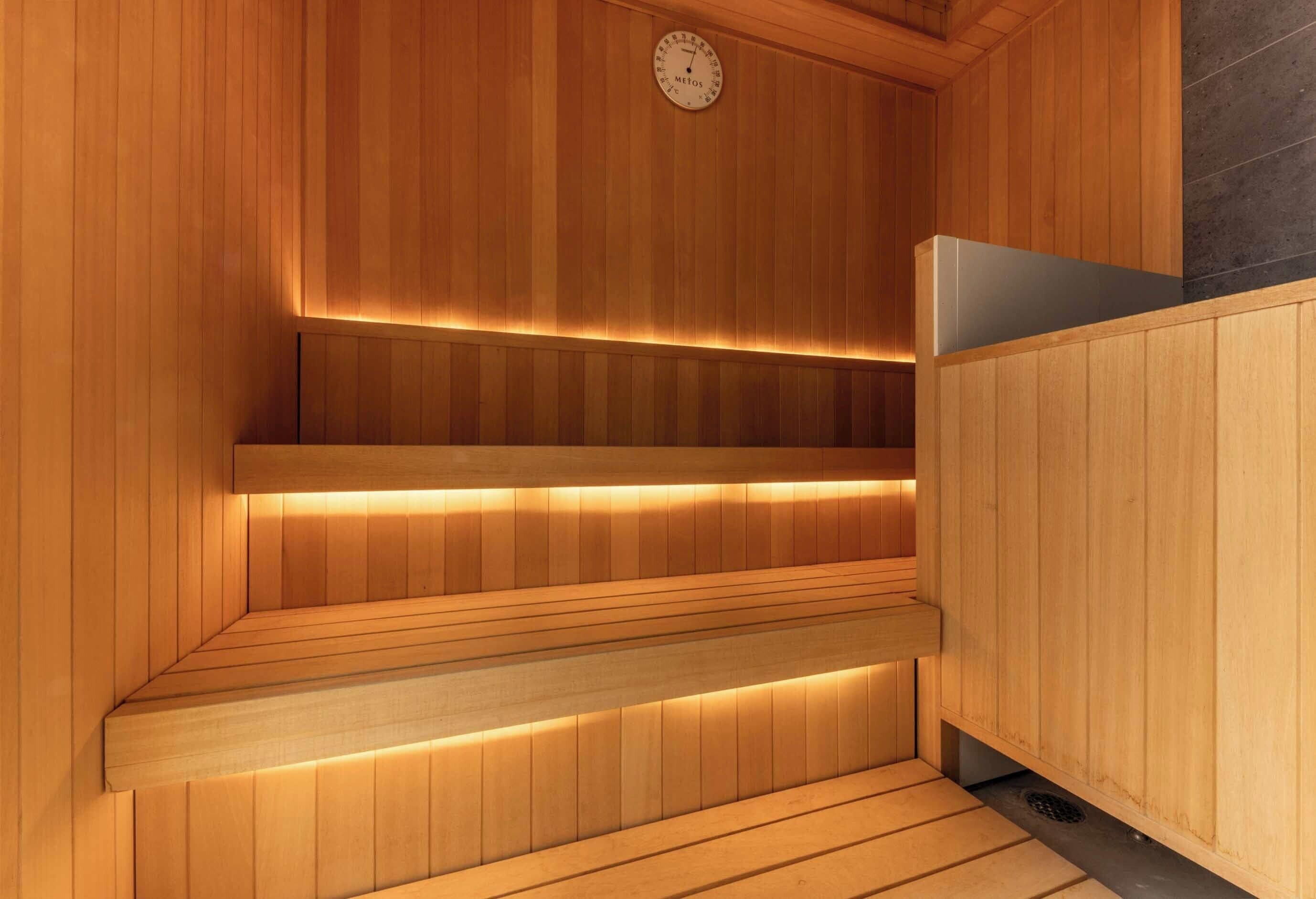 Un sauna en bois, doté de bancs et d’un thermostat visible.