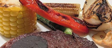 A plate with grilled vegetables and a steak.