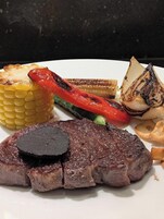 Un plato con verduras a la parrilla y un bistec.