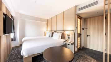 A hotel room with a bed, bedside table, lamp, and a TV.