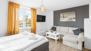 A modern hotel room with a bed, a sofa, a coffee table, and a TV. - In the middle of Kempten with a mountain feel (Kempten (Allgäu))
