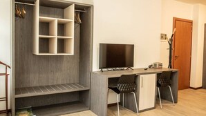 A modern room with a built-in desk, two chairs, a television, and a wardrobe with multiple shelves. - Appartamento - Edolo (Edolo)