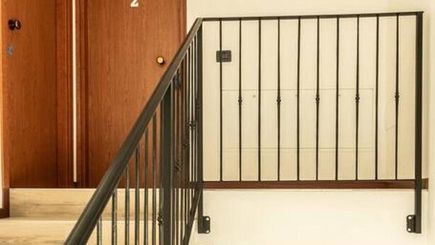 A staircase with a black metal railing, wooden doors, and a light-colored wall. - Appartamento - Edolo (Edolo)