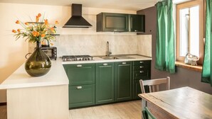 Een keuken met groene kastjes, een wit aanrecht, een fornuis en een raam met groene gordijnen.