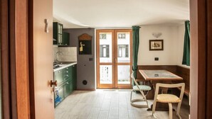 Una cocina con armarios verdes, una mesa de comedor con dos sillas y vistas a través de un ventanal.