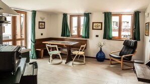 Una habitación acogedora con una mesa de madera, dos sillas, un jarrón azul y una silla negra.