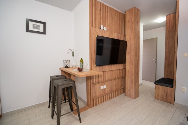 A modern kitchen with a wooden accent wall, a built-in TV, and a bar stool.