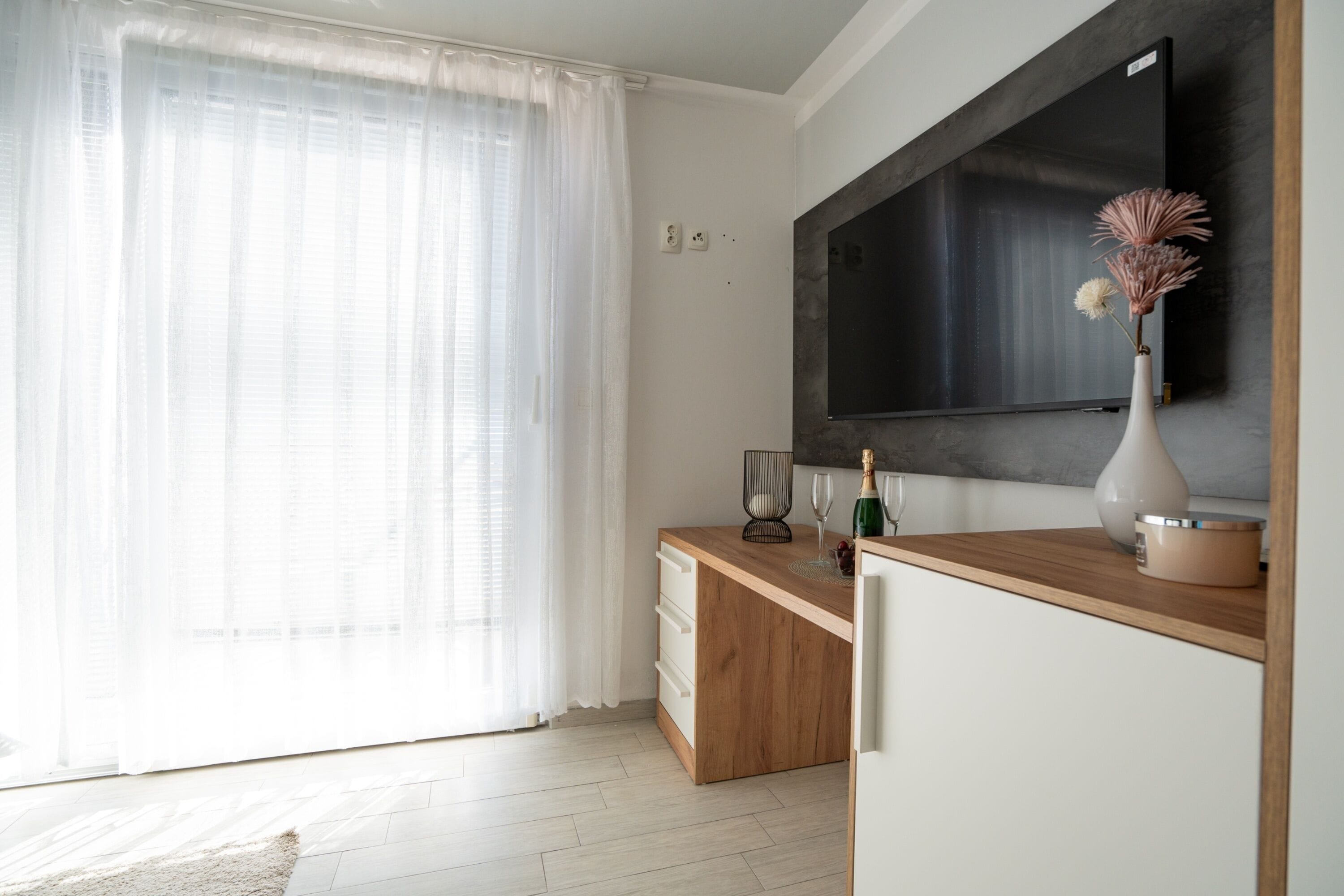 A modern kitchen with a wooden countertop, a built-in oven, and a large flat-screen TV mounted on the wall.