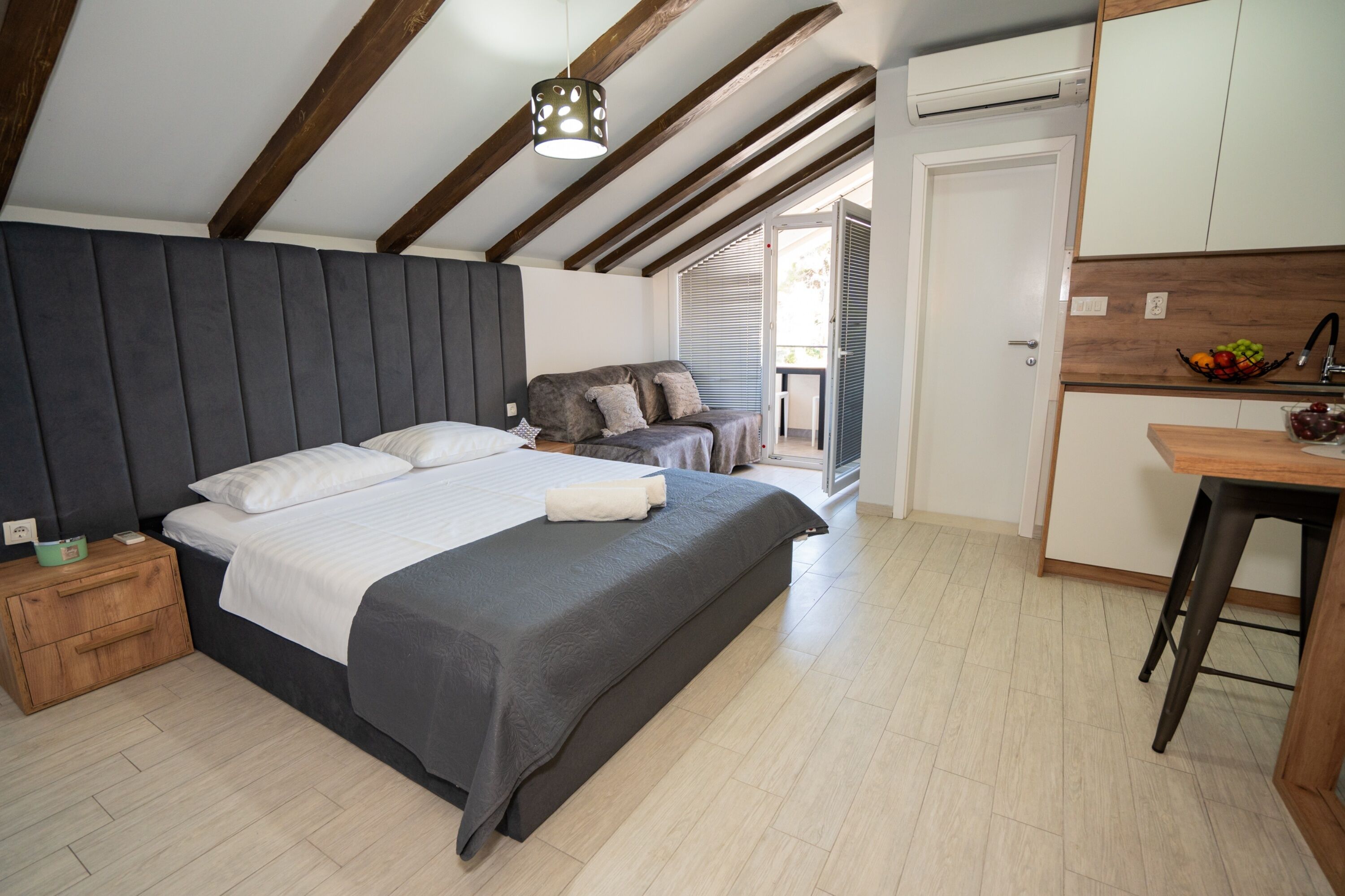 A bedroom with a large bed, wooden nightstand, and a small table with fruit.