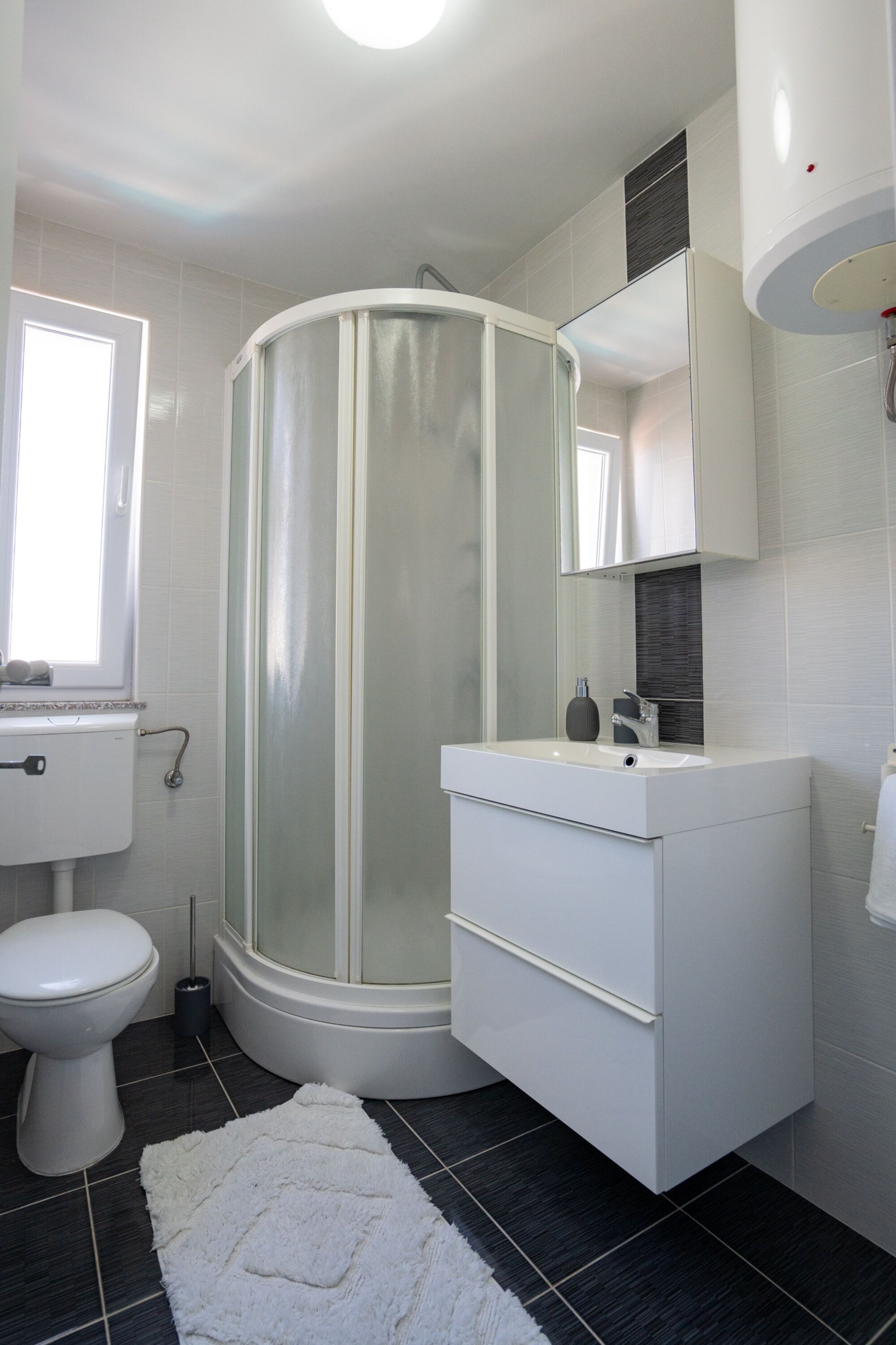 A modern bathroom with a glass-enclosed shower, a white sink, and a toilet.