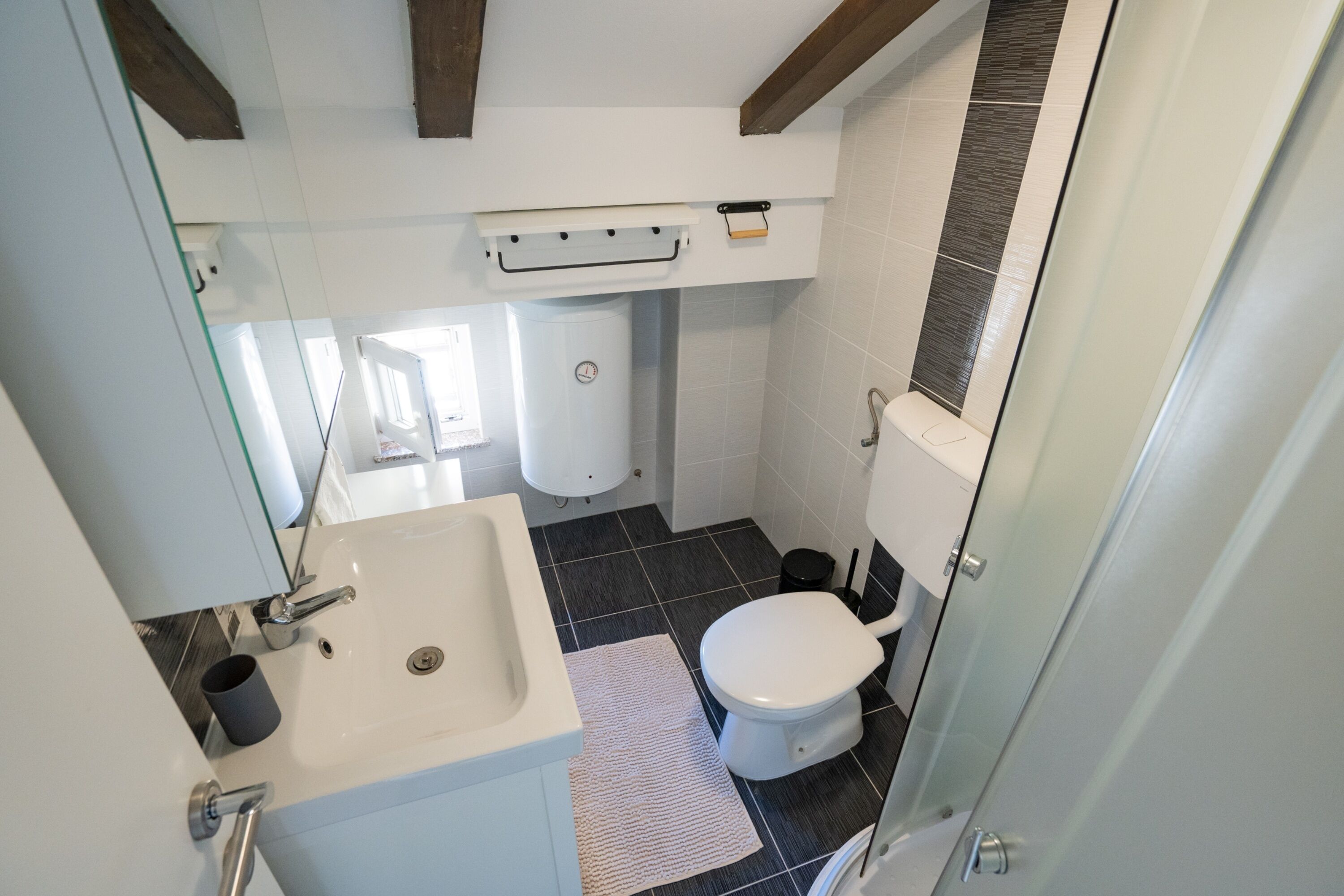 A compact bathroom with a white sink, toilet, and a small window.