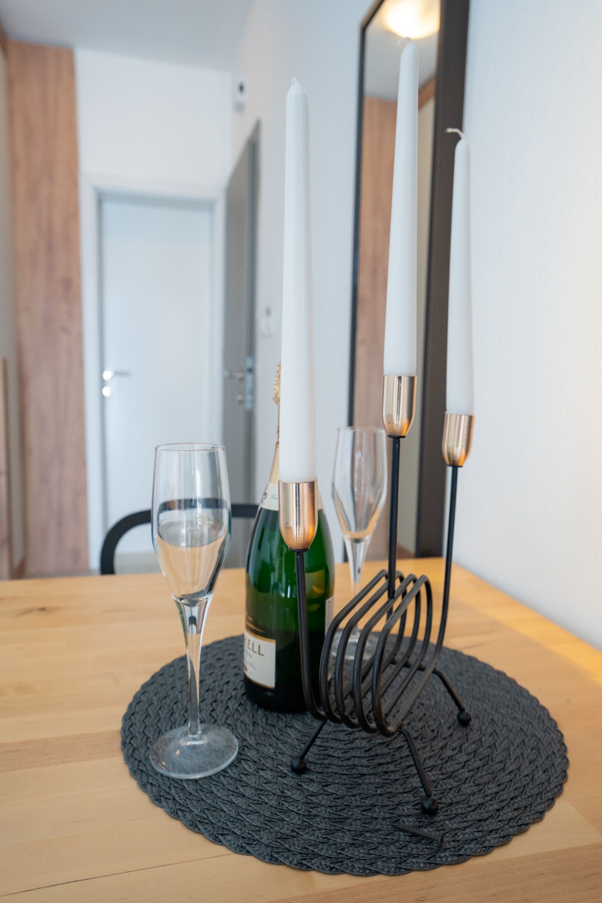 A table with a bottle of wine, two wine glasses, and a candle holder with candles.
