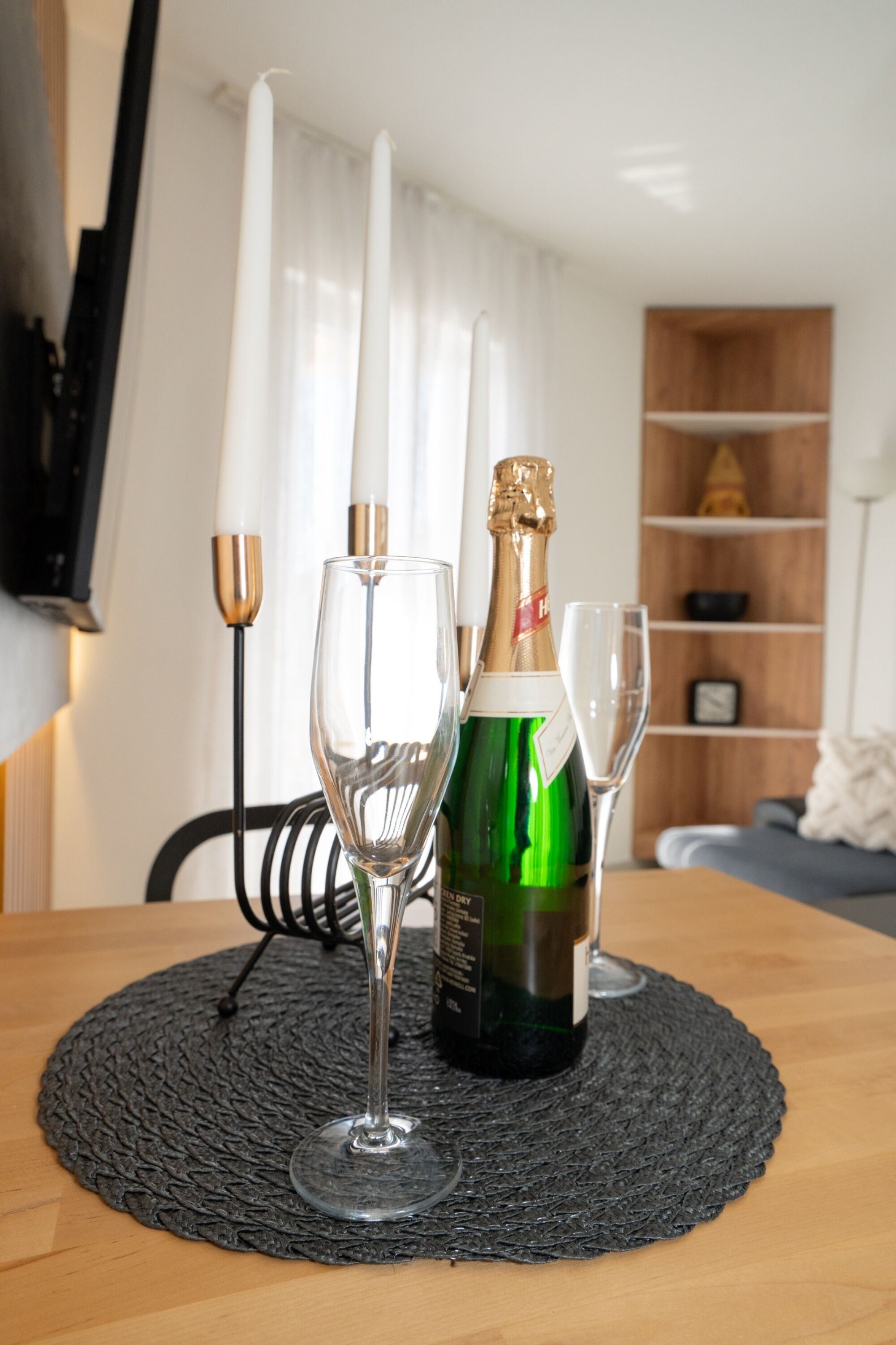 Une table avec une bouteille de champagne, deux verres et un chandelier.