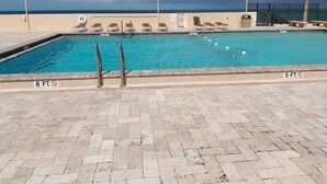 En swimmingpool med udsigt til stranden, liggestole og et livredder-tårn.