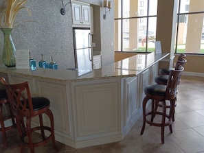 Una cocina con encimera de granito, armarios blancos y un ventanal amplio.