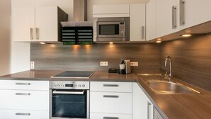 Een moderne keuken met roestvrijstalen apparatuur, witte kasten en een houten achterwand.